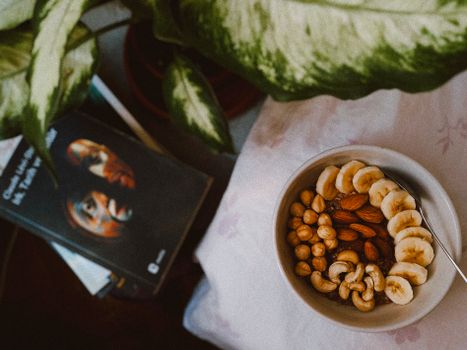 A nutritious breakfast bowl featuring bananas, nuts, and seeds in a cozy setting.