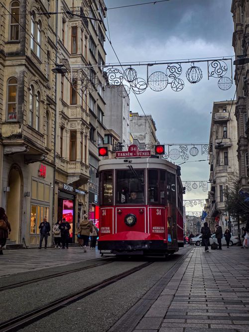 Free Red tram traverses İstiklal Avenue in İstanbul, surrounded by old architecture and bustling pedestrians. Stock Photo