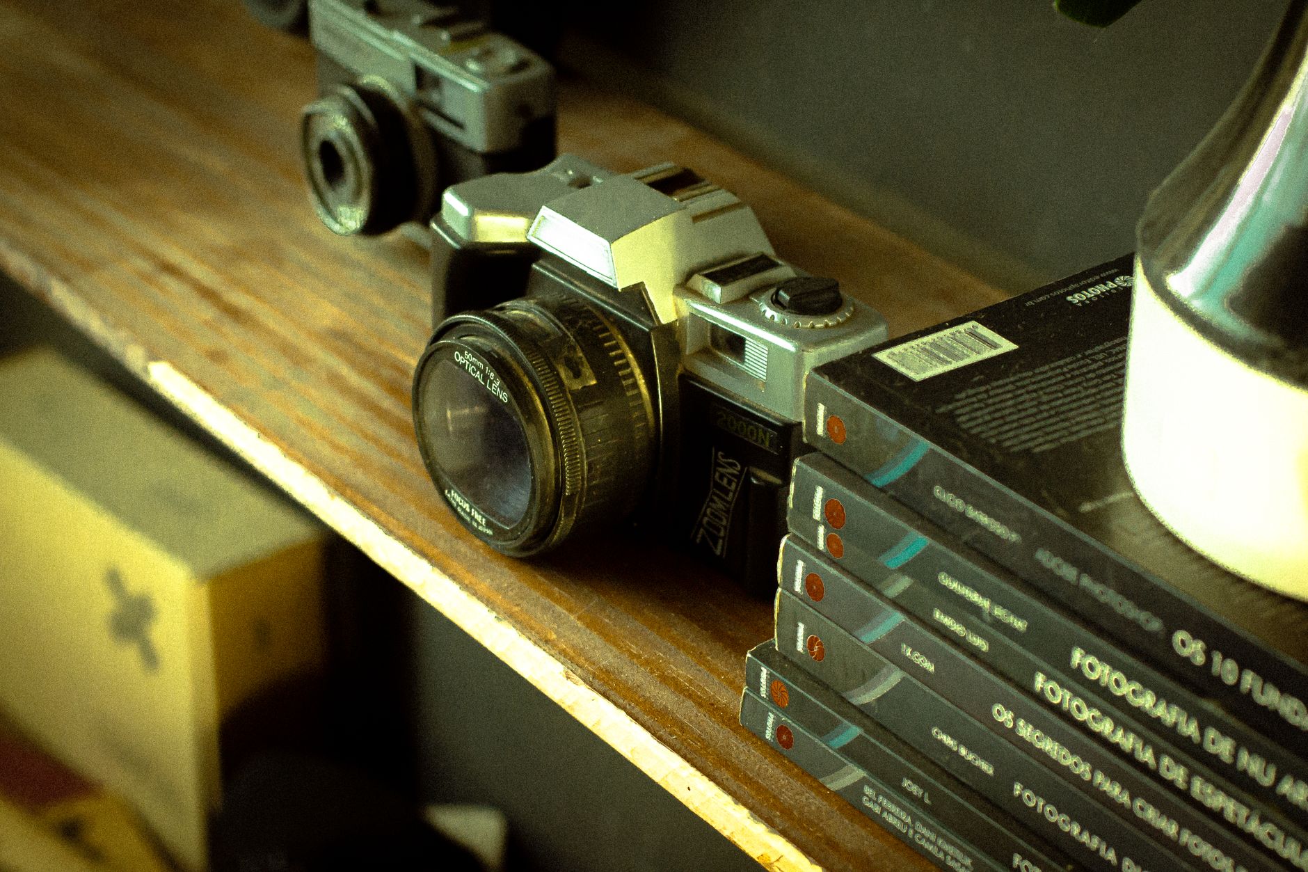 A retro camera on a wooden shelf with photographic books, evoking nostalgia.