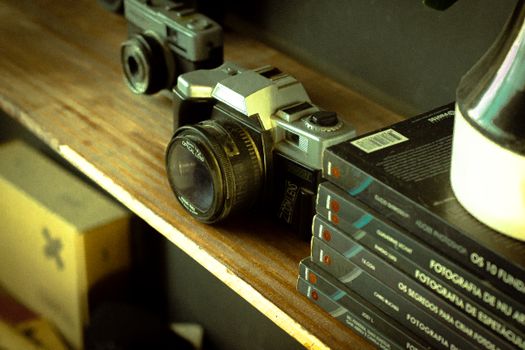 A retro camera on a wooden shelf with photographic books, evoking nostalgia.