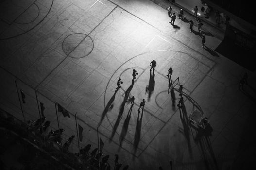 Aerial black and white photo capturing shadows on a basketball court during night play in Vietnam.