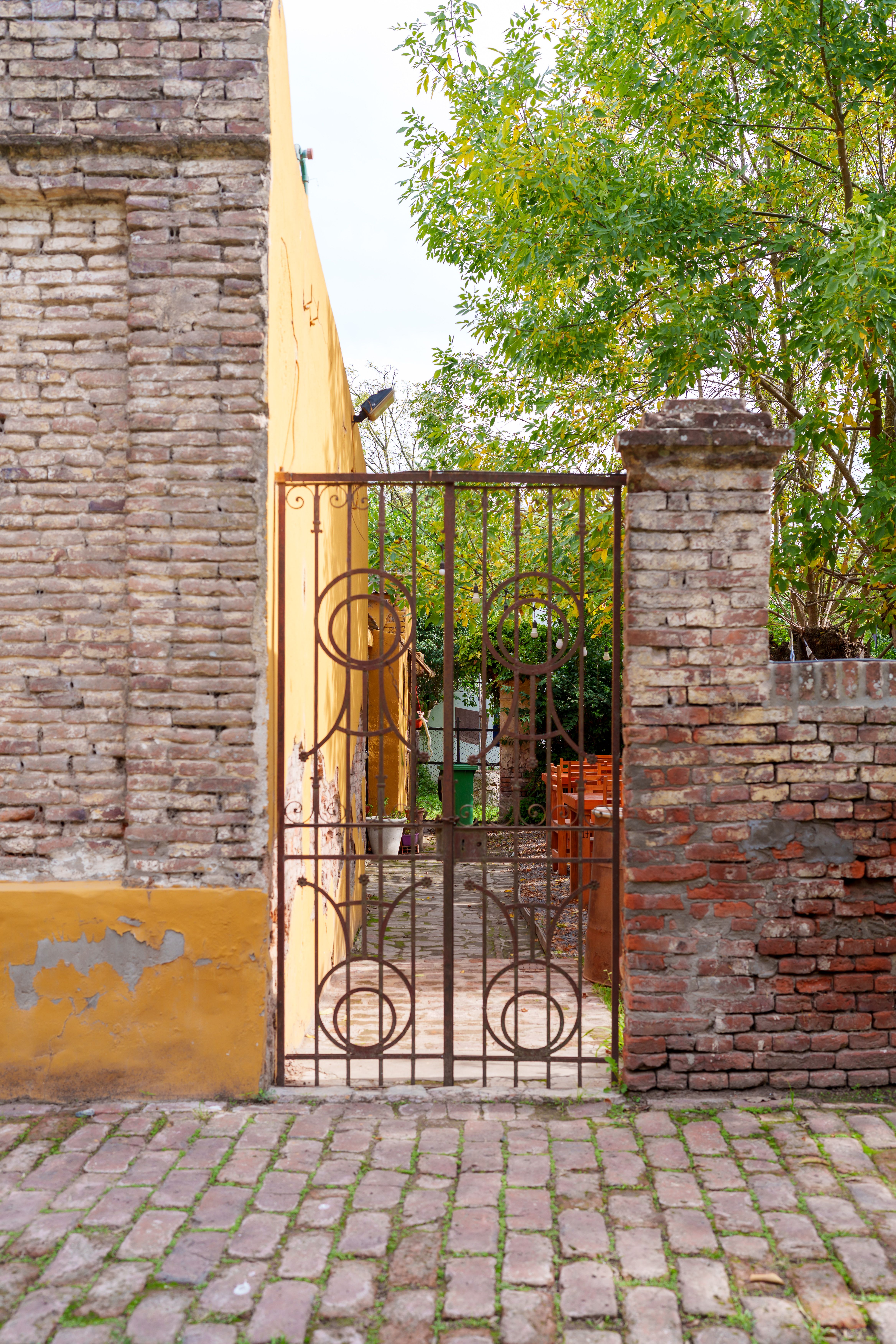 A rustic iron gate in Uribelarrea, Buenos Aires, Argentina, showcasing charming brick architecture.