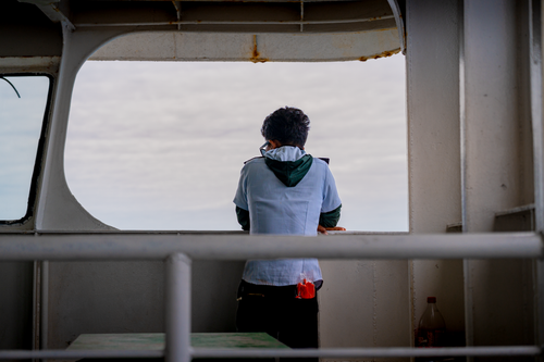 Free A person standing on a ship deck gazing at the ocean horizon in San Remigio, Philippines. Stock Photo