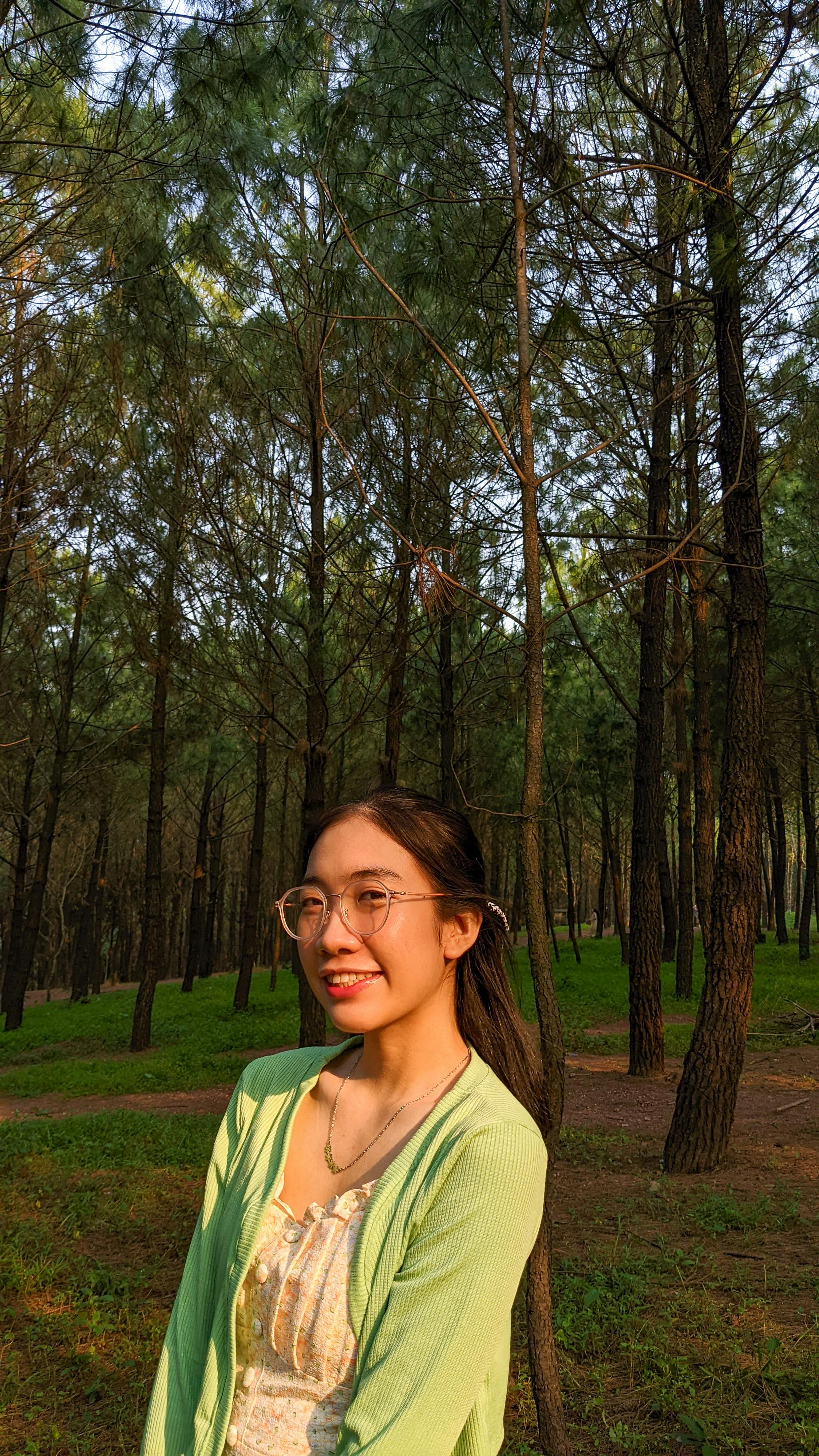 A woman smiling in a sunlit forest in Thành phố Huế, capturing the essence of Vietnam's natural beauty.