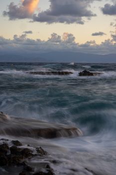 Captivating view of ocean waves crashing against rocks at sunset, creating a dynamic seascape.