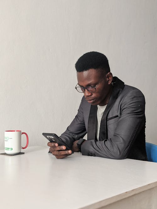 Mann, Der Schwarzen Anzug Trägt, Während Smartphone Hält