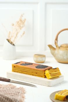 Appetizing Lapis Legit cake displayed elegantly on a marble tray with rustic tea set.