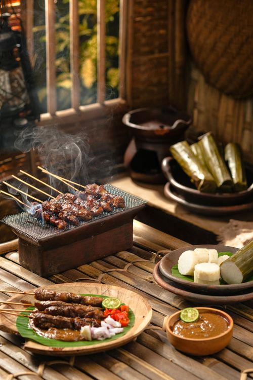 Free Grilled Indonesian satay skewers served with rice cakes and sauce in a rustic setting. Stock Photo
