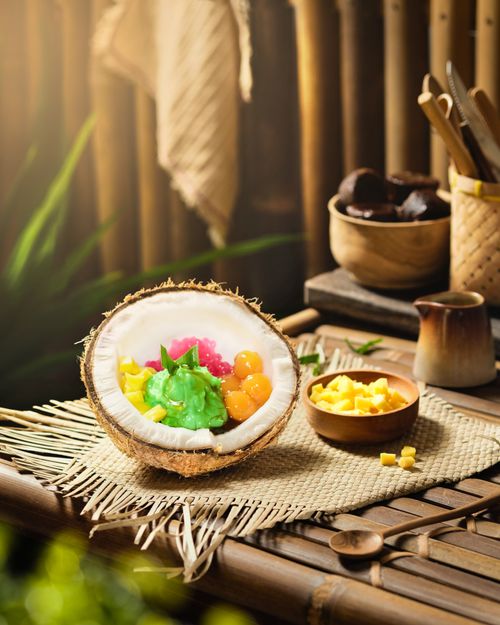 Free Vibrant Indonesian dessert served in a coconut shell on a bamboo table setting. Stock Photo