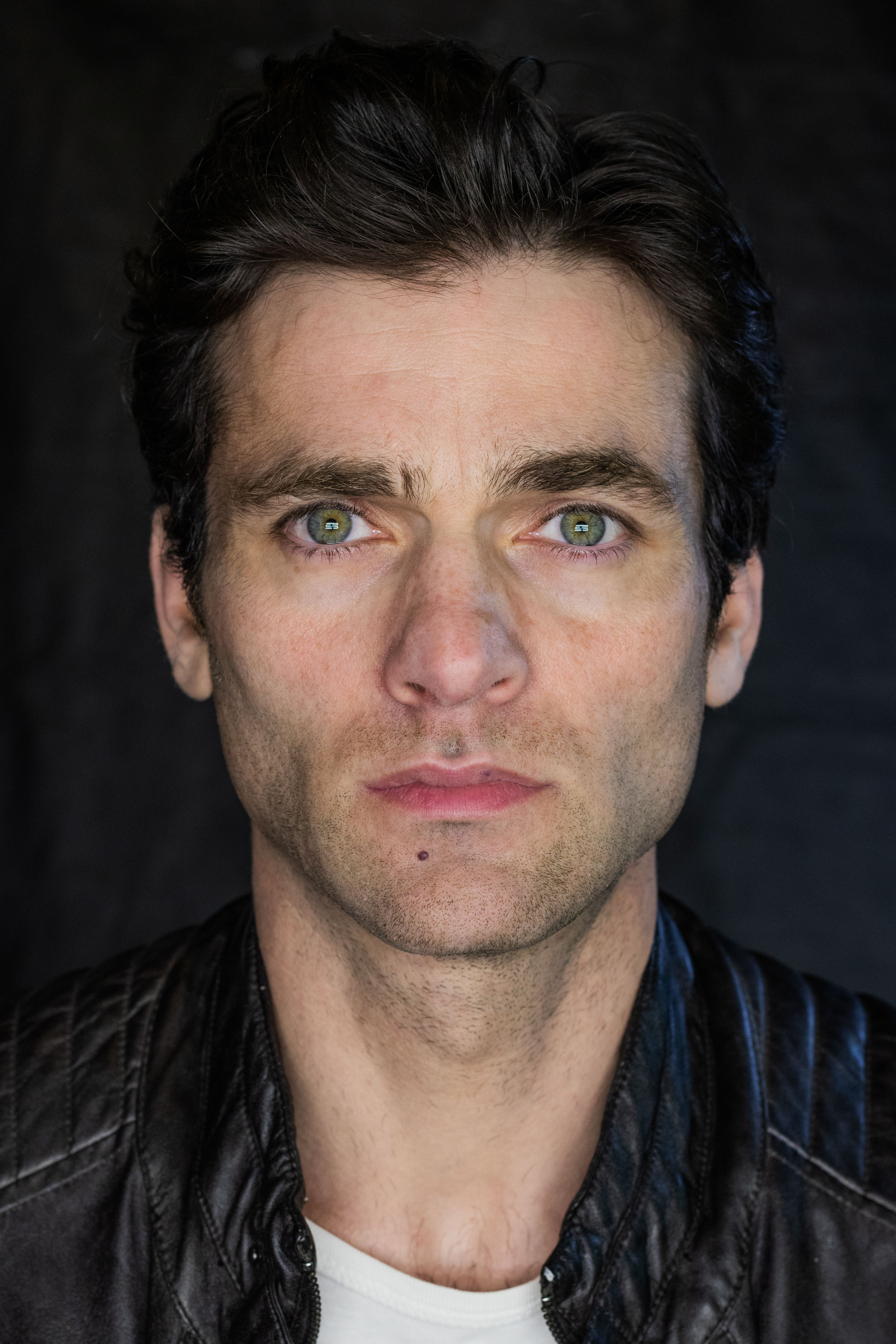 Close-up portrait of a man in a leather jacket with intense expression.
