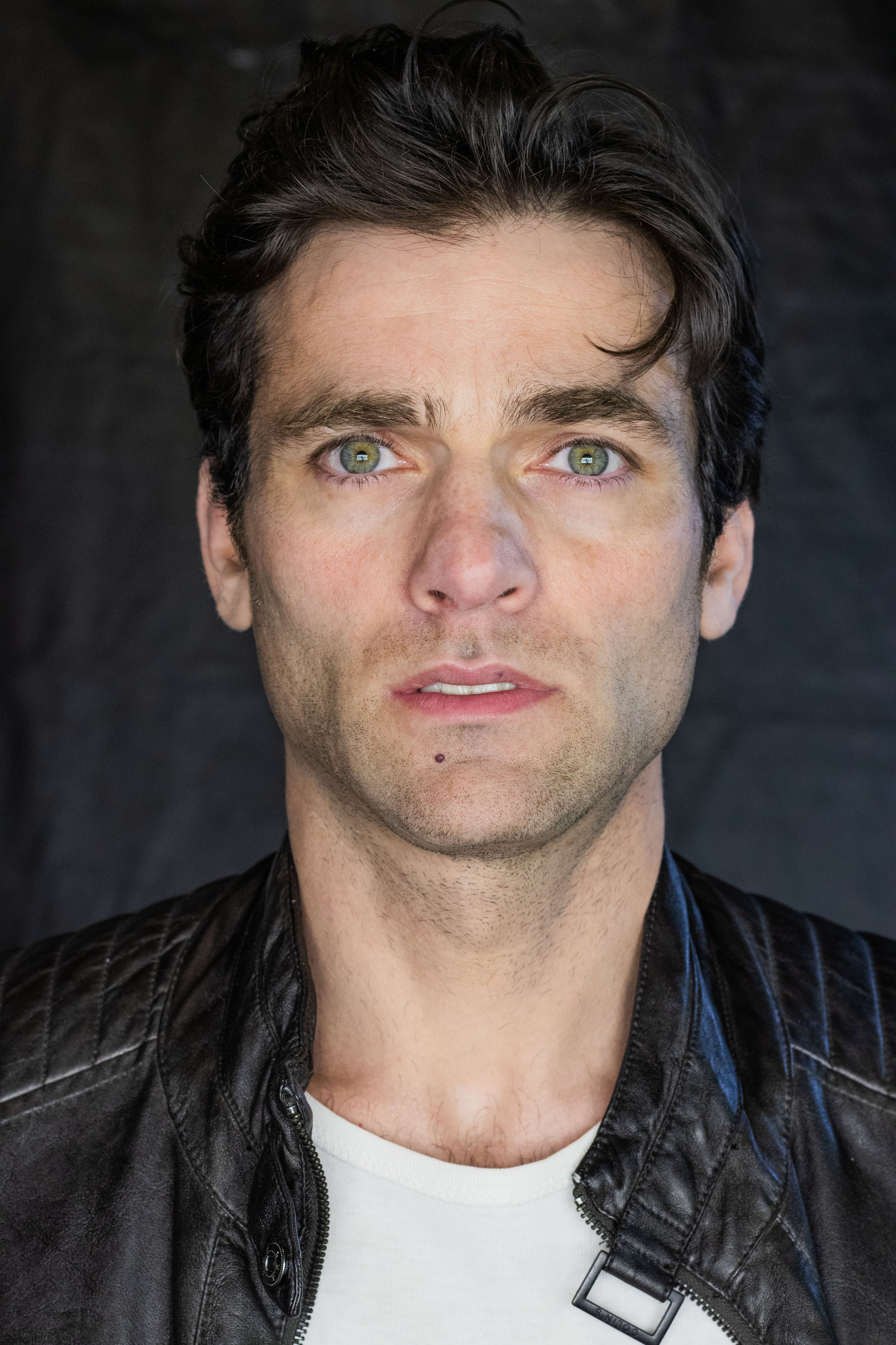 Close-up portrait of a man wearing a leather jacket with a neutral expression.