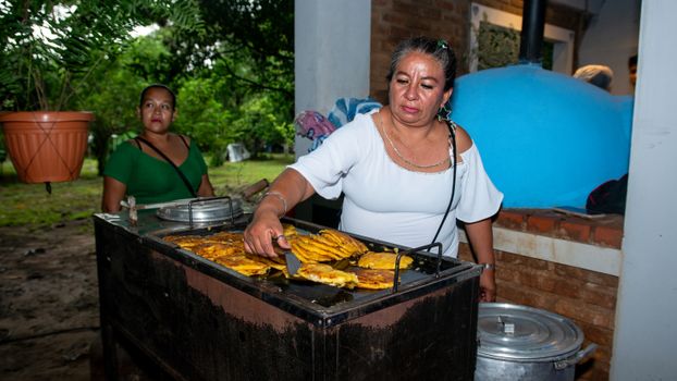 Woman cooking traditional Bolivian snacks outdoors in Santa Cruz de la Sierra.