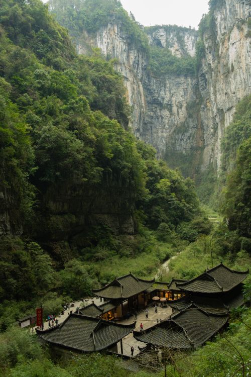 Free Panoramic view of an ancient Chinese building nestled within a lush green gorge. Stock Photo