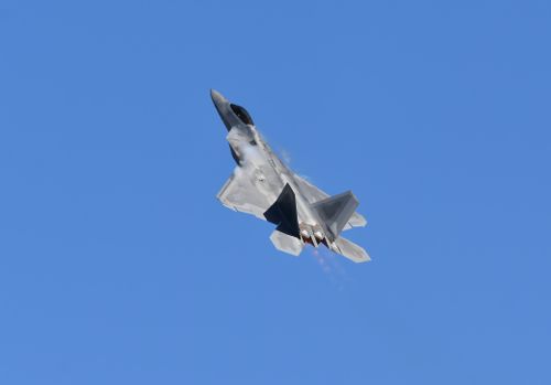 Free Military jet fighter captured during a dynamic aerial performance against a clear blue sky. Stock Photo