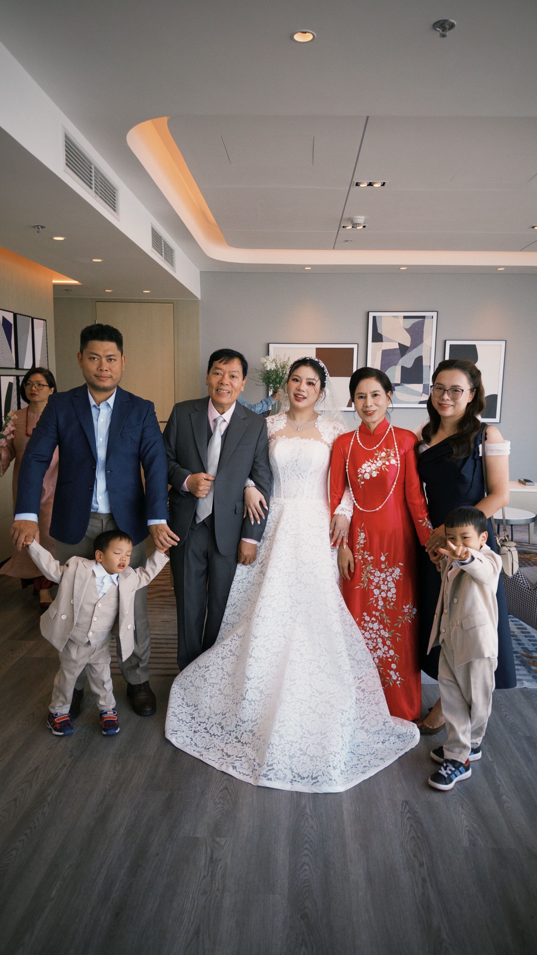 Vietnamese family poses in traditional attire during a joyful wedding celebration indoors.