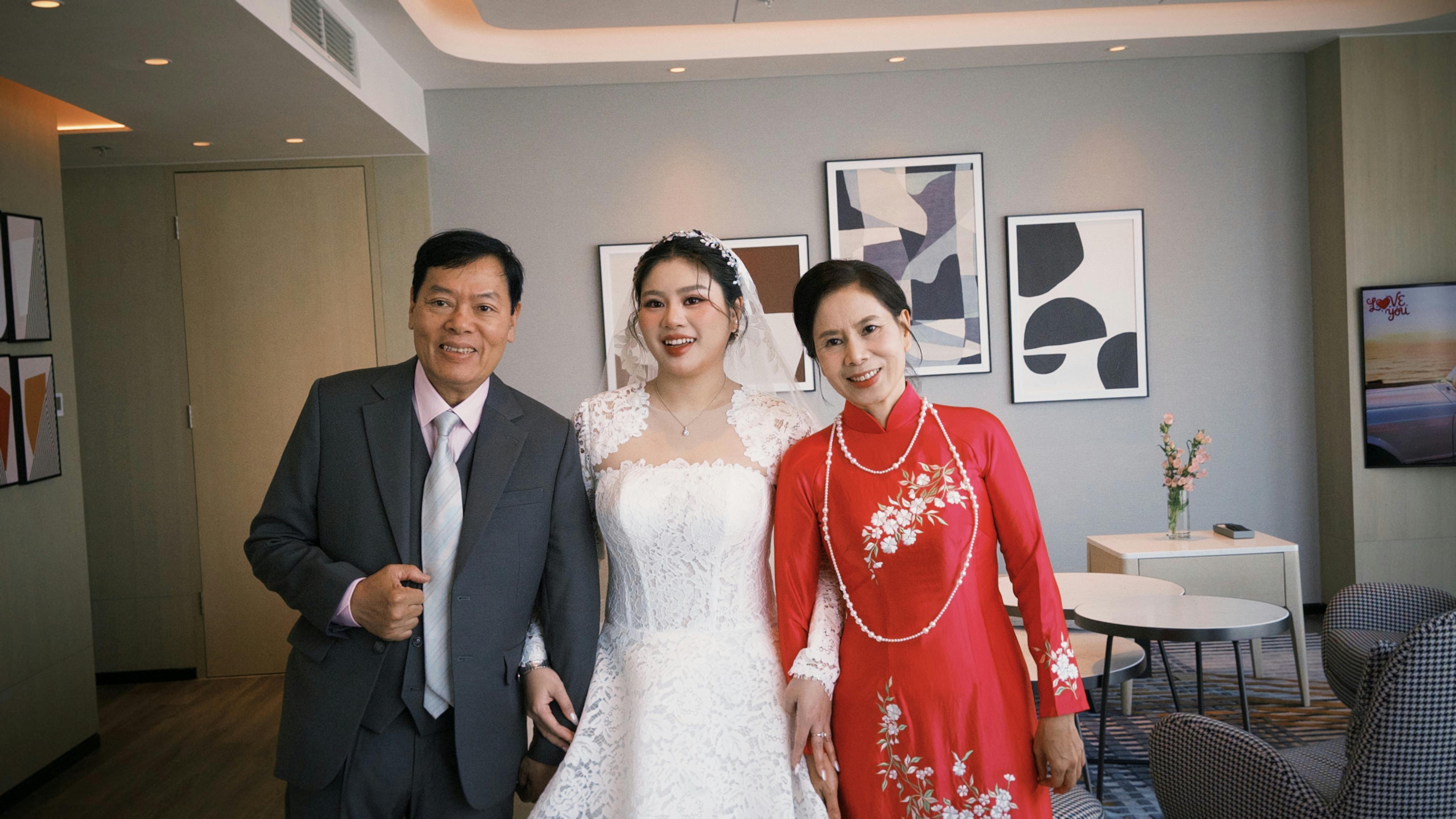 Beautiful Vietnamese bride with family in traditional attire at a wedding indoors.
