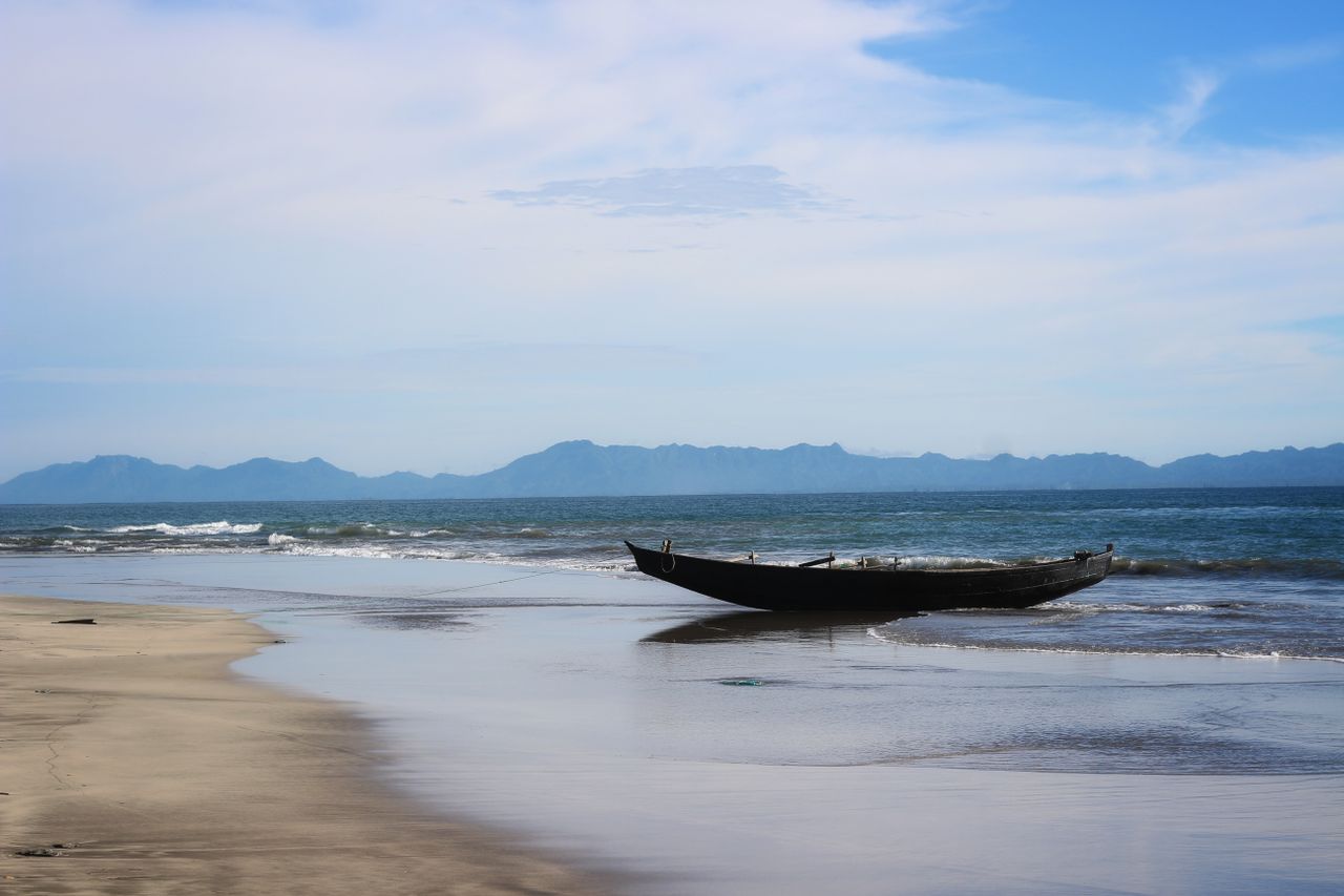 tranquil beach scene in bangladesh featuring an empty boat at the sea