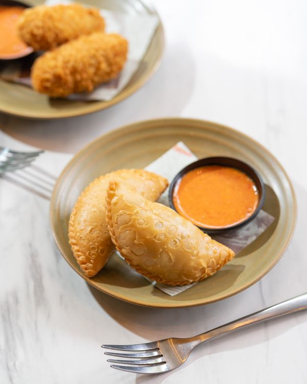 Gratuit Une assiette de pastel indonésien accompagné d'une sauce piquante, parfait pour une collation salée. Photos