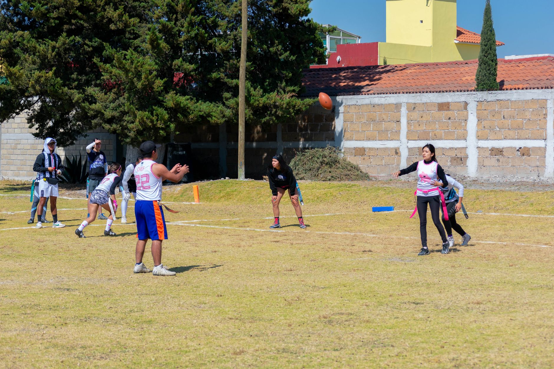 Energetic youth flag football match on a sunny day in Toluca de Lerdo, Mexico, with players in action.