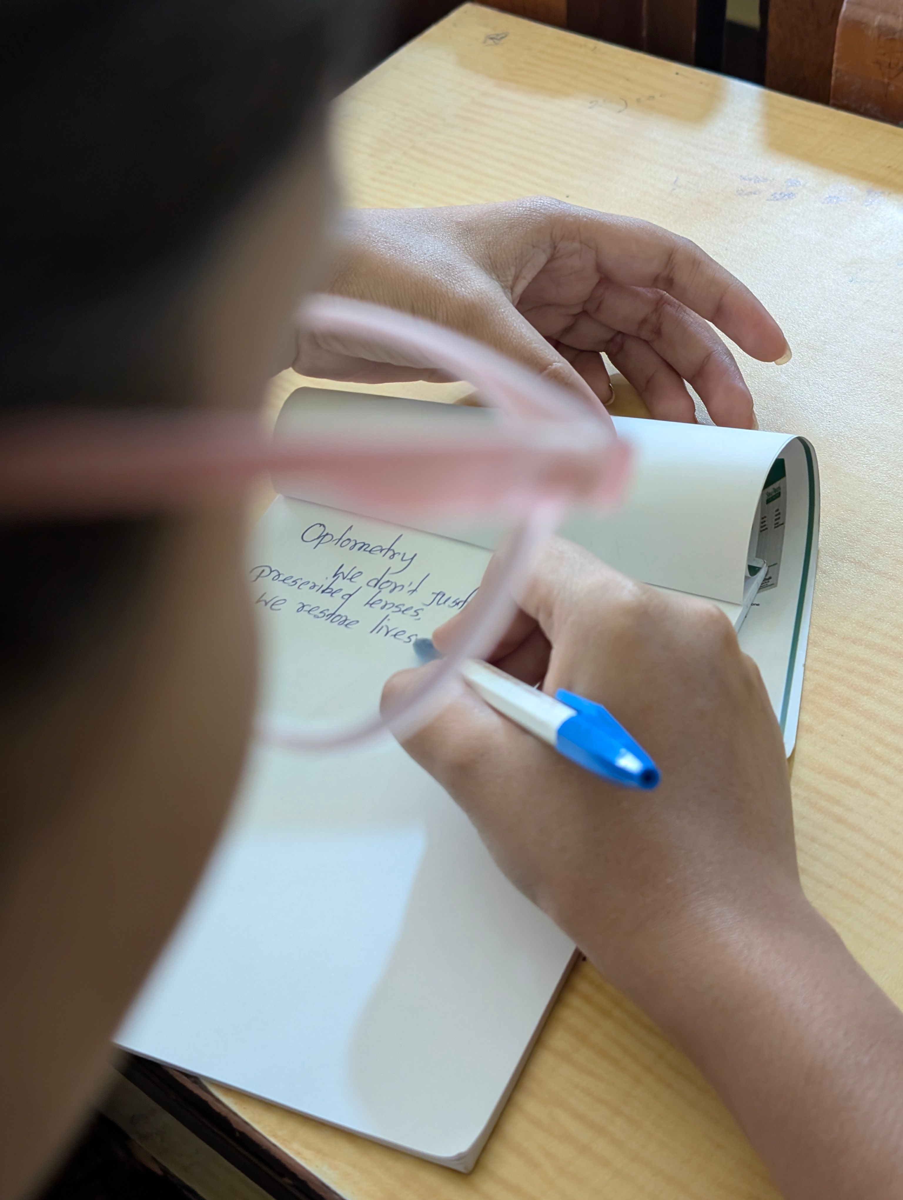 A clean kitchen counter with a single capsule, a glass of water, and a small notebook with handwritten notes