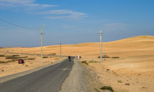 Free A scenic asphalt road through the Moroccan desert with dunes and clear blue sky. Stock Photo
