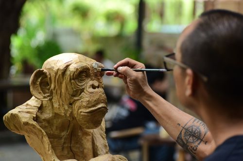 Free A skilled artisan carves an intricate wooden chimpanzee sculpture outdoors. Stock Photo