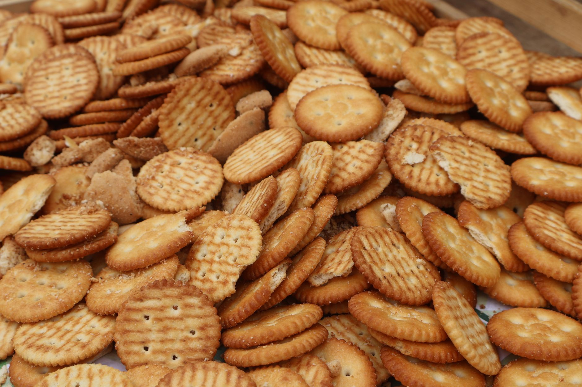 A collection of assorted round crackers stacked in a pile, perfect for snacking or party platters.