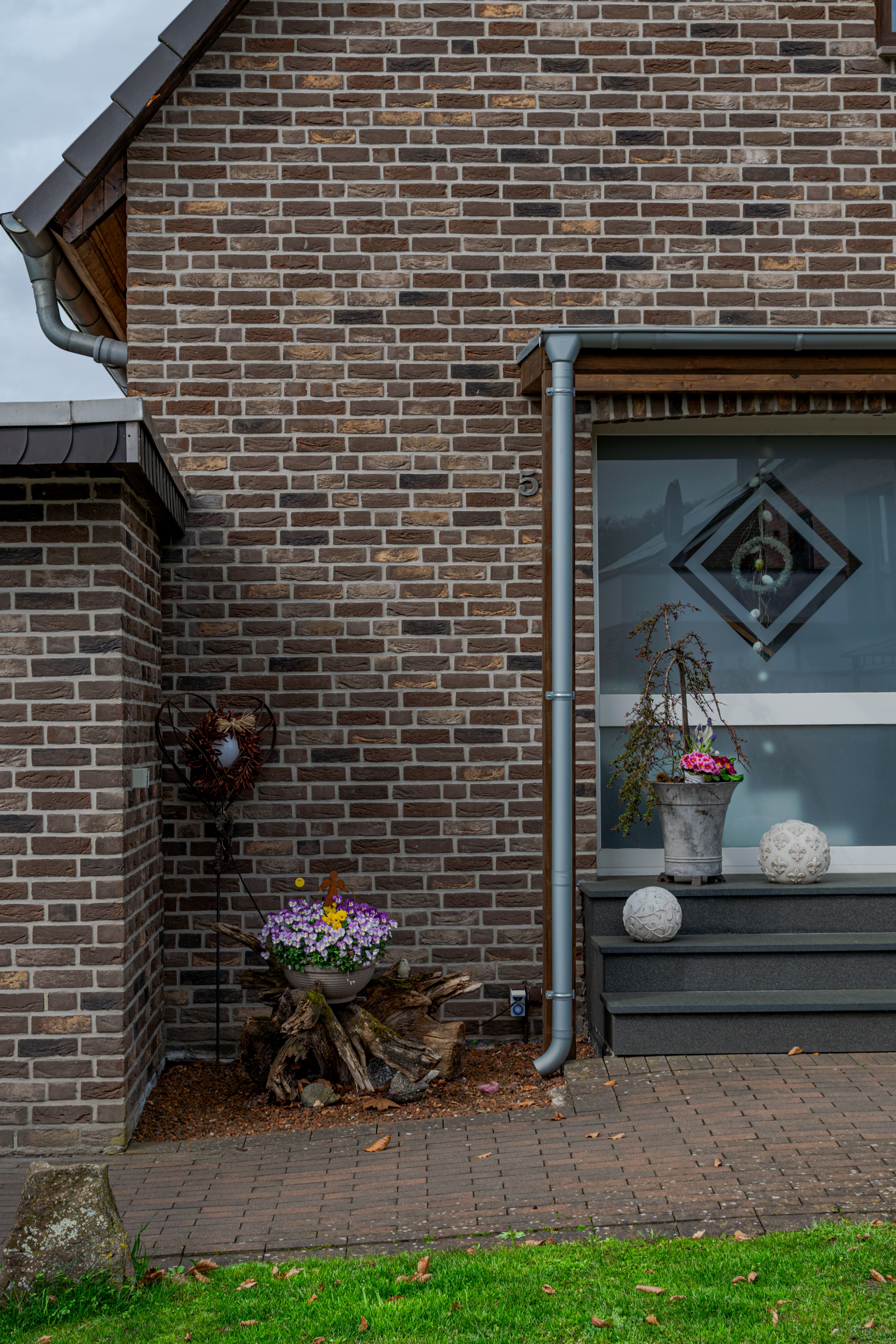 Klinker-Fassade eines deutschen Einfamilienhauses mit Fenster, Eingangstreppe und Gartendekoration