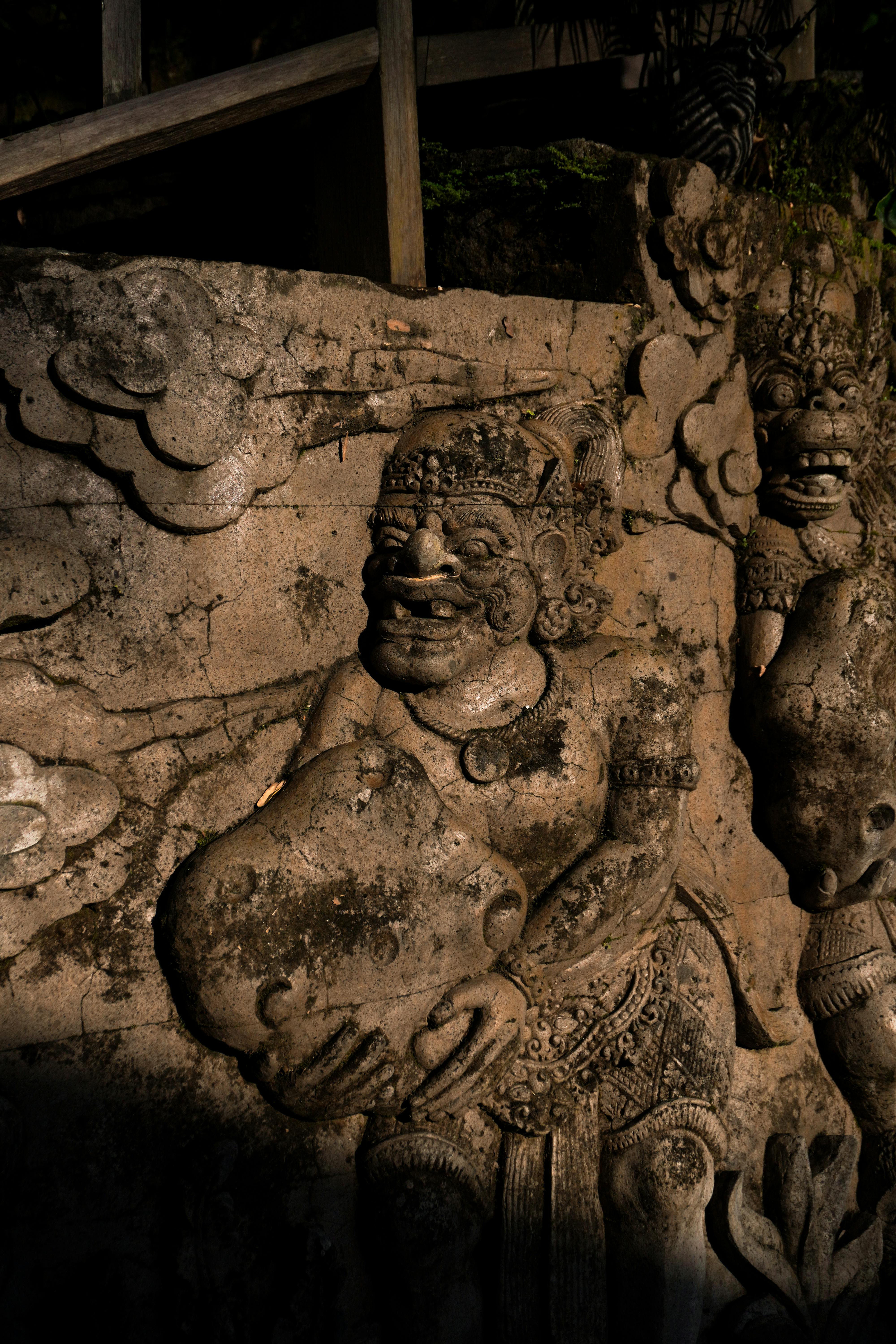 Hand-carved stone reliefs of Balinese Hindu figures along the Ayung River cliffside near Ubud during white water rafting