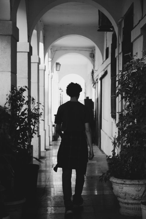 Free A person strolling through a narrow, monochrome archway in Alger Centre, Algeria. Stock Photo
