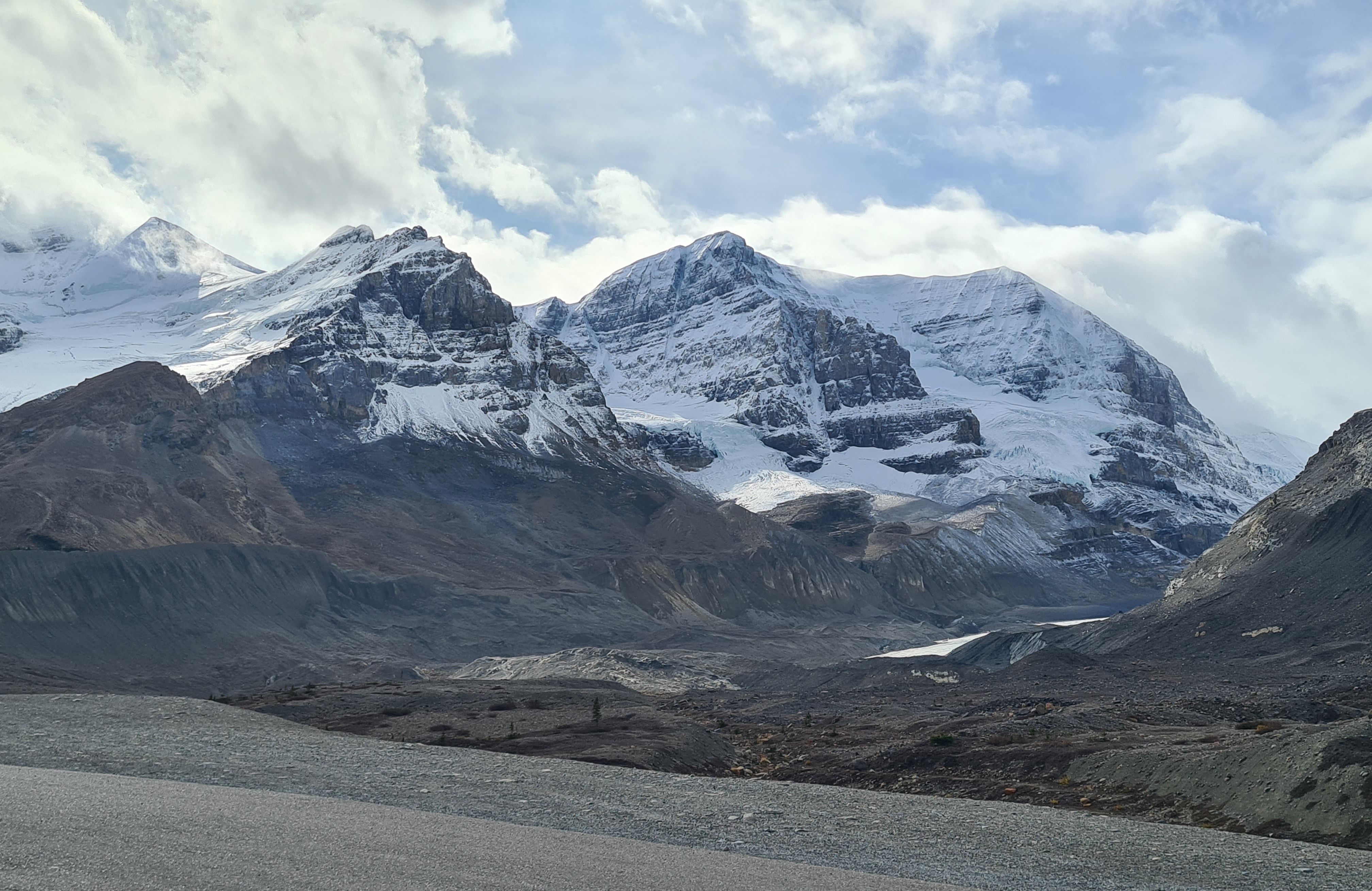 Snow-covered peaks in Jasper National Park, Alberta, Canada, under a bright cloudy sky.