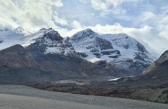 Snow-covered peaks in Jasper National Park, Alberta, Canada, under a bright cloudy sky.