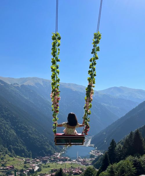 Free A girl on a decorative swing overlooking Uzungöl Lake against a backdrop of lush mountains. Stock Photo