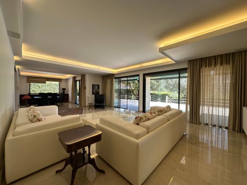 Free Spacious modern living room featuring large windows, elegant sofas, and warm lighting. Stock Photo
