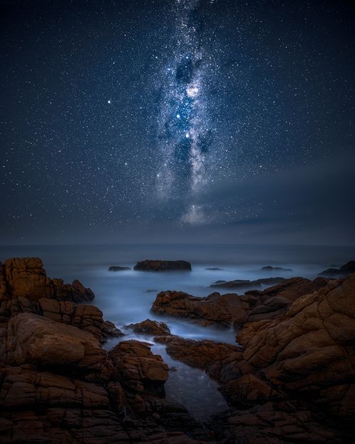 Free Captivating night sky with Milky Way above Victoria Bay's rugged coastline in South Africa. Stock Photo