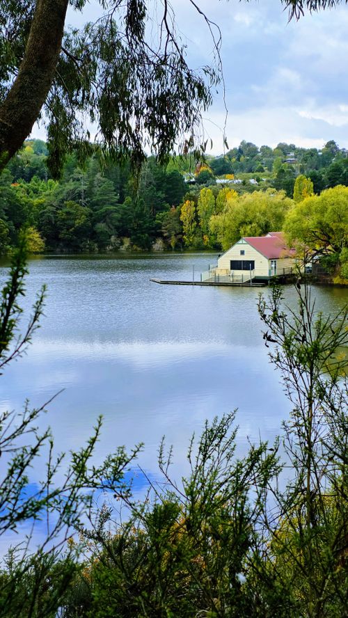 Free Tranquil view of a boathouse by a lake surrounded by lush greenery in Daylesford, Australia. Stock Photo