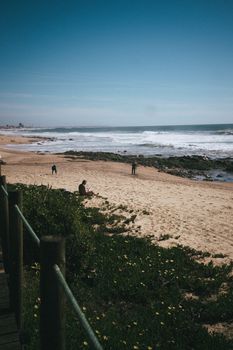 A serene beach scene with people enjoying the seaside in Porto, Portugal.