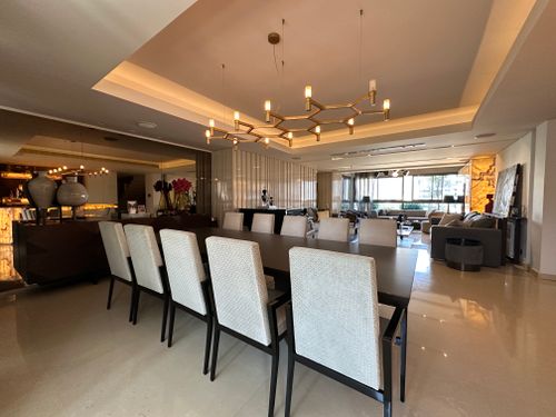 Free Spacious open-plan living room with elegant dining set and modern chandeliers, exuding luxury and comfort. Stock Photo