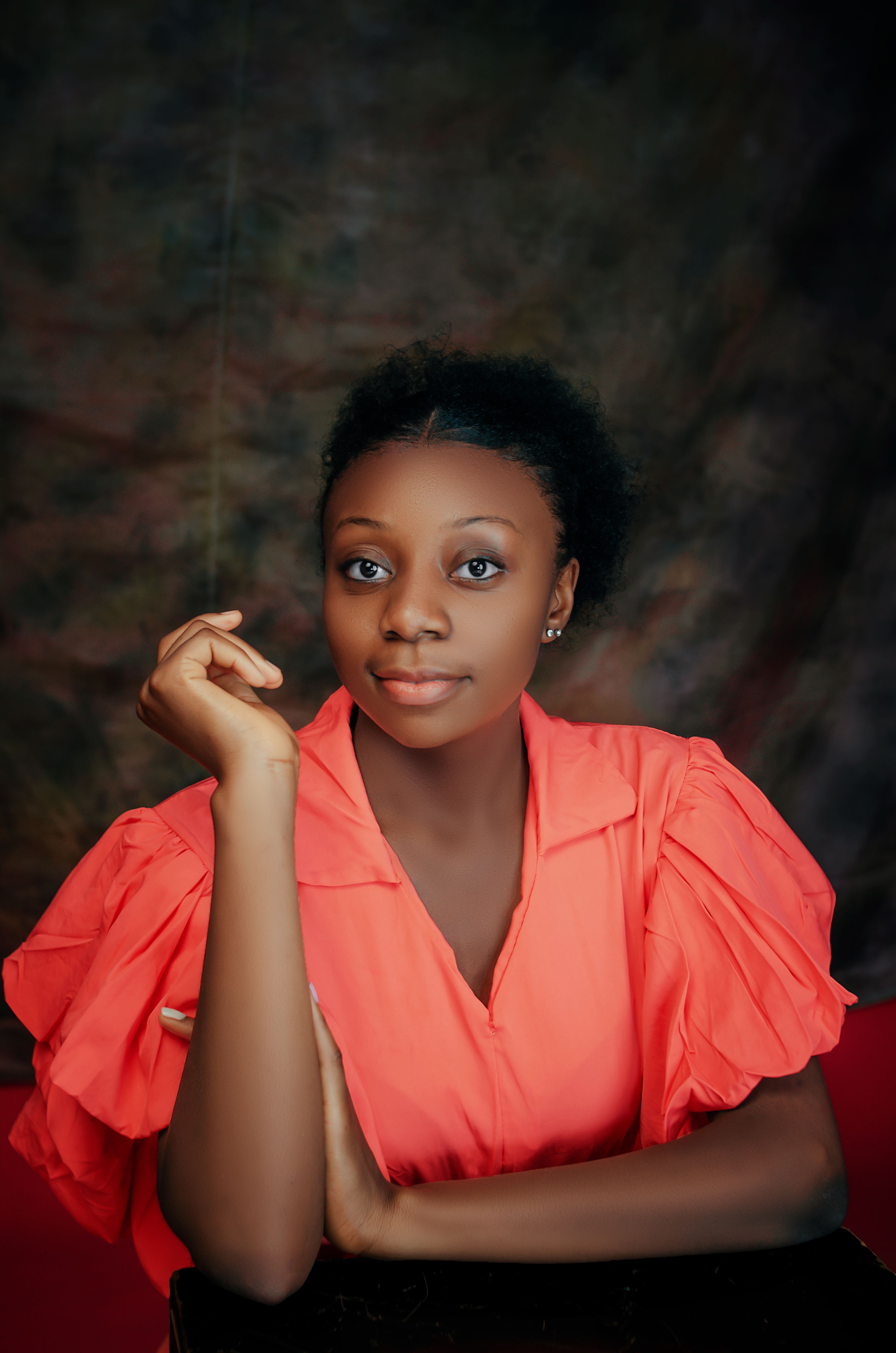 Charming portrait of a young woman posing indoors with a warm expression and stylish red blouse.