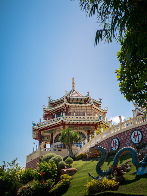 Traditional Taoist temple in Cebu City with vibrant gardens and dragon decoration, under clear blue sky.