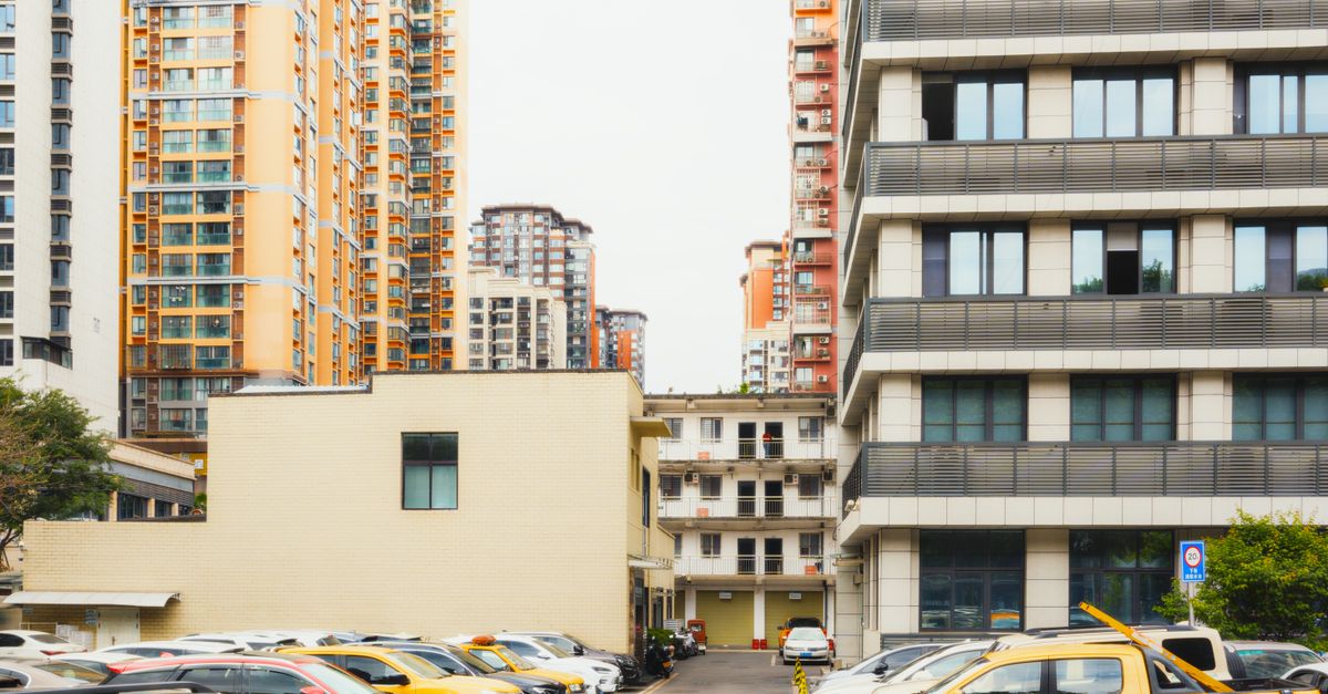 High-rise apartment buildings with parked cars in front captured in Sichuan, China.