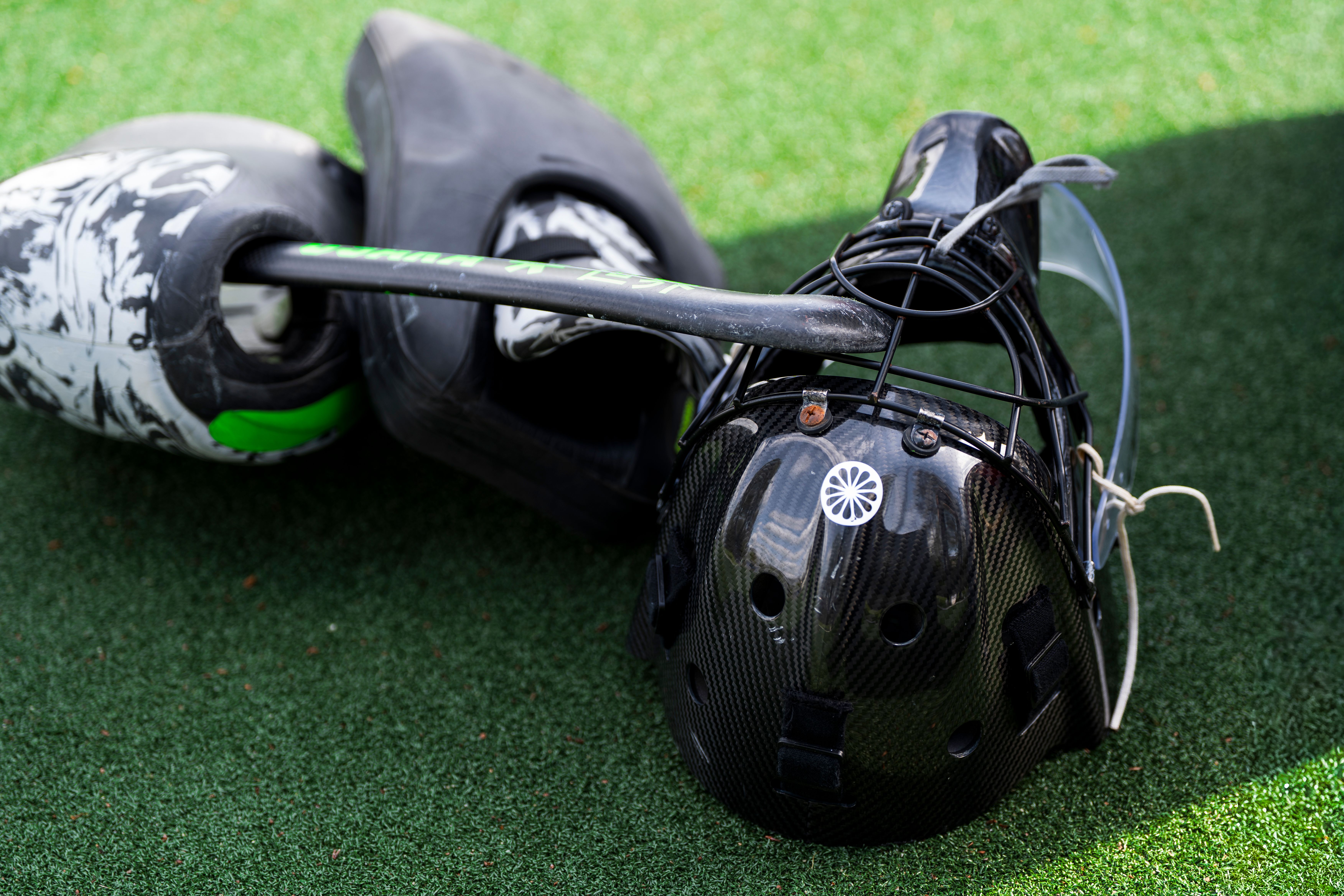 Catcher's helmet and pads on artificial turf, standard baseball equipment.