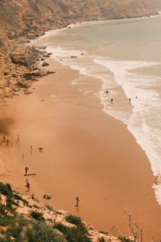 Beach scene with surfers and rocky cliffs, perfect for summer travel and adventure themes.