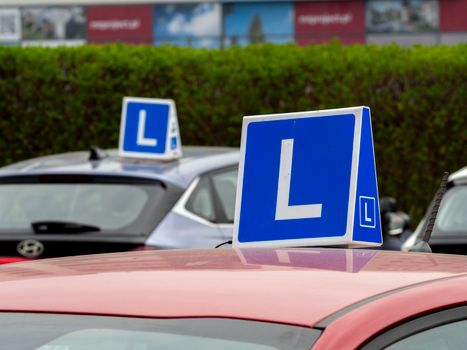 Cars with learning signs parked outdoors in Wrocław, Poland, at a driving school training area.