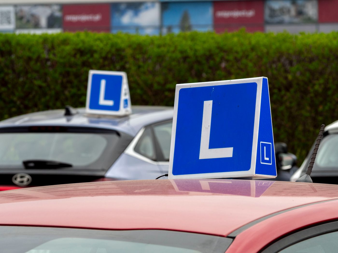 A driving-school car with a learner sign parked outside