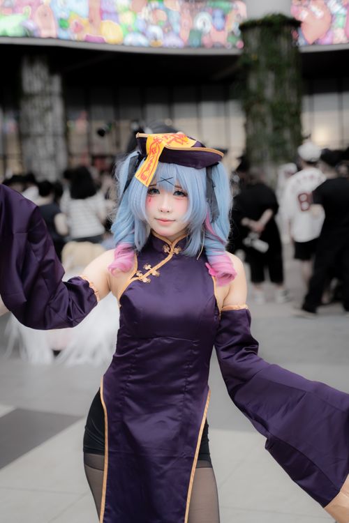 Cosplayer u šarenom kostimu na konvenciji s publikom u pozadini