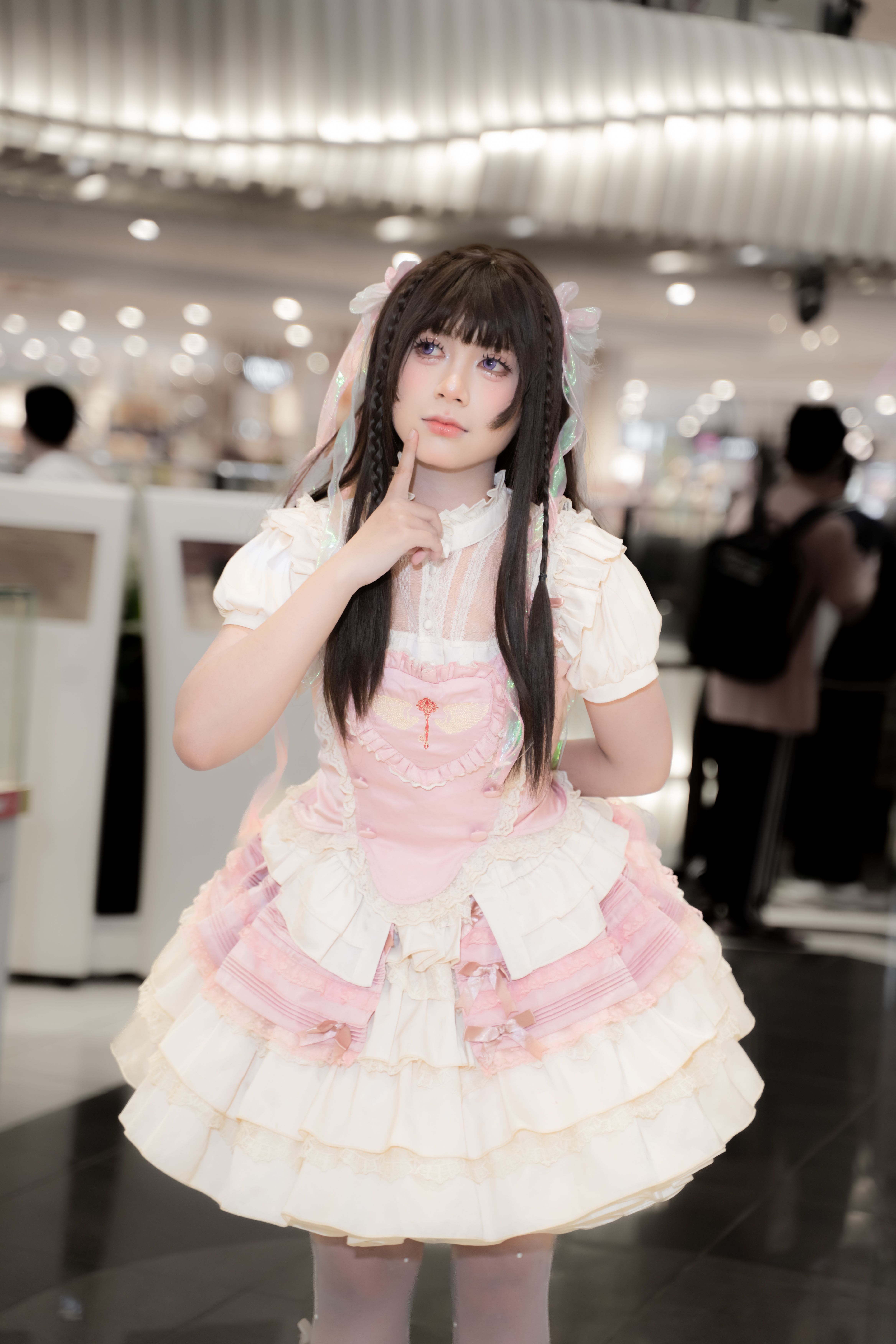 Young woman in Lolita attire poses stylishly in a bustling mall.