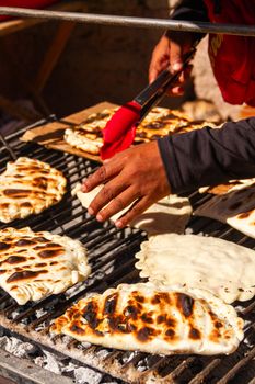 Close-up of traditional flatbread grilling on an open grill outdoors.