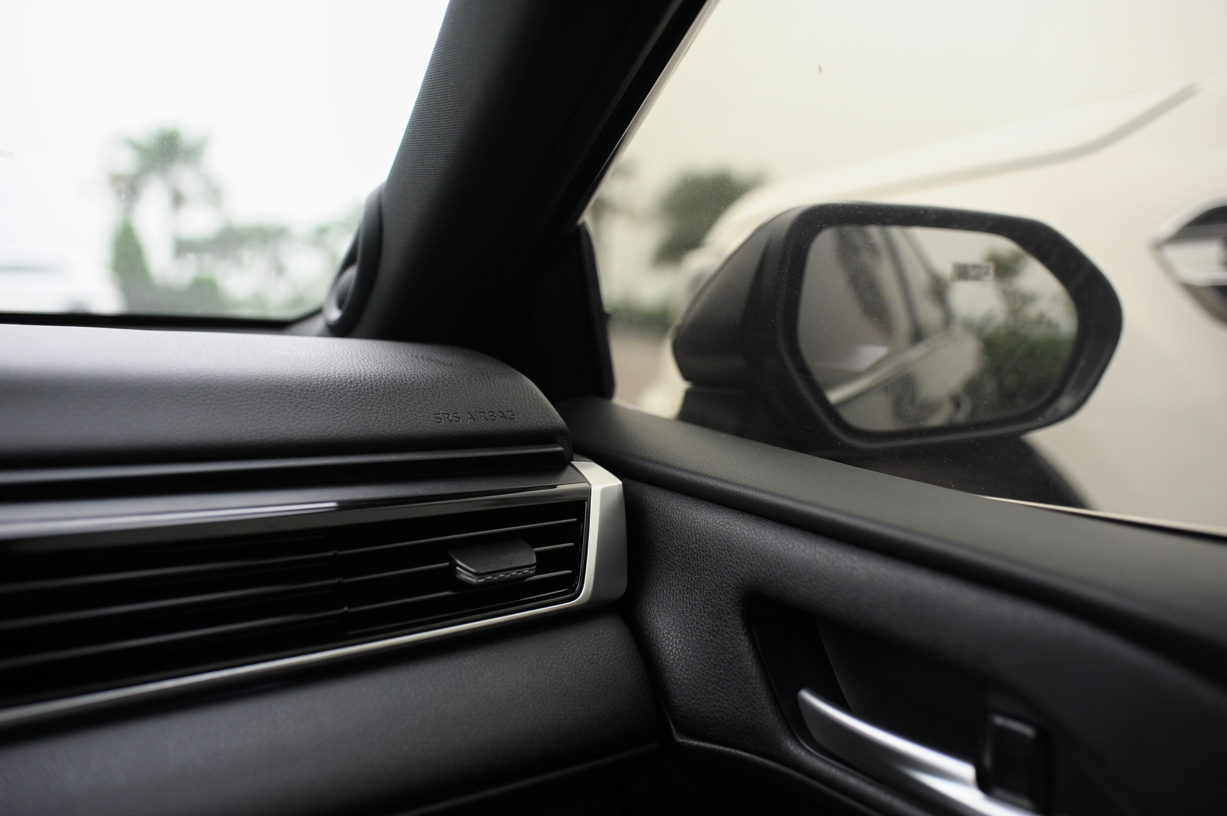 A sleek car interior with focus on side mirror reflecting another car.