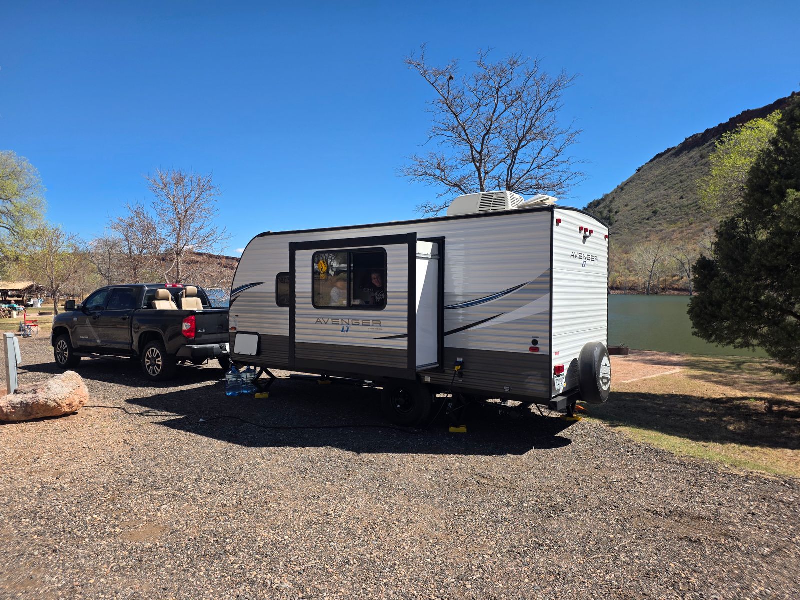 Travel trailer and truck parked by a lake for camping